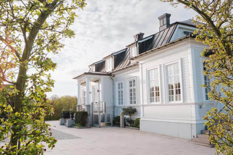 Vacker vit villa vid Eriksberg med träd och grönska.